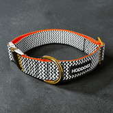 Dog collar with black and white pattern and orange accents on a dark gray background