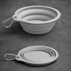Collapsible gray dog bowl with carabiner on a dark surface